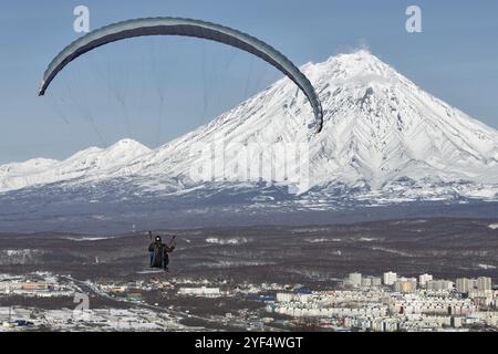 PETROPAVLOVSK-KAMTSCHATSKI, KAMTSCHATKA, RUSSLAND, 21. NOVEMBER 2014: Gleitschirmfliegen über Petropavlovsk-Kamtschatski-Stadt auf dem Hintergrund des aktiven K Stockfoto