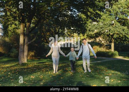 Eine Familienmutter und zwei Söhne haben Spaß, laufen im Park und springen. Söhne, Kinder, Mutter, laufen, spielen, freuen Sie sich, genießen Sie die Natur im Sommer. Familienmitglied Stockfoto