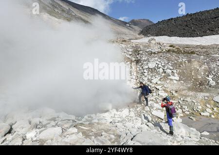 NATURPARK NALYCHEVO, VULKAN DZENZUR, HALBINSEL KAMTSCHATKA, RUSSISCHER FERNOST, 4. SEPTEMBER, 2014: Junge Männer und Frauen, Touristen, die Fumarole rauchen Stockfoto