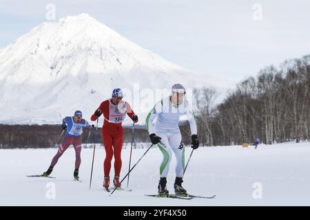 PETROPAVLOVSK STADT, KAMTSCHATKA HALBINSEL, RUSSISCHER FERNOST, 10. Februar 2018: Skifahrer laufen auf der Winterskipiste vor dem Hintergrund des Vulkans Korjak Stockfoto