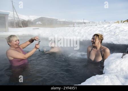 KAMTSCHATKA HALBINSEL, RUSSLAND, 2. Februar 2013: Zwei fröhliche Frauen fotografierten im Winter beim Schwimmen im geothermischen Spa im Thermalbecken. Eurasien, Russland Stockfoto