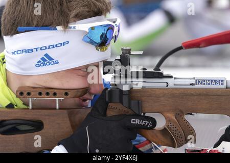 Nahaufnahme sportlicher Biathlet mit Gewehrschießen in Bauchlage. Biathlet Morilov Michail im Schießstand. Junior Biathlon Wettbewerbe Ost Stockfoto