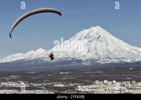 PETROPAVLOVSK-KAMTSCHATSKI, KAMTSCHATKA, RUSSLAND, 21. NOVEMBER 2014: Gleitschirmfliegen über Petropavlovsk-Kamtschatski-Stadt auf dem Hintergrund des aktiven K Stockfoto