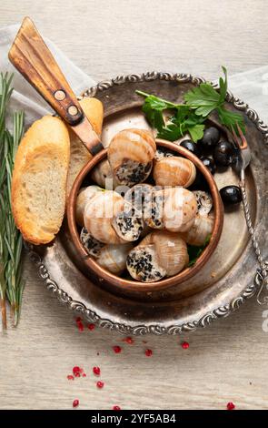 Teller mit gebackenen Schnecken gefüllt mit Knoblauchbutter auf hellem Hintergrund. Draufsicht. Stockfoto