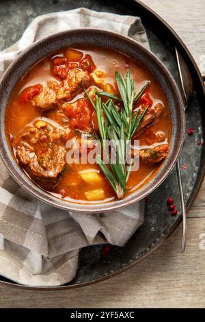 Beef Strips Bourgeon mit Karotten und kleinen Zwiebeln in grauer Schüssel auf hölzernem Hintergrund. Draufsicht. Stockfoto