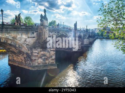 PRAG - 10. MAI 2024: Touristen wandern auf der Karlsbrücke in Prag mit Prager Burg und Moldau im Hintergrund an sonnigen Sommertagen Stockfoto
