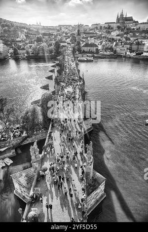 PRAG - 10. MAI 2024: Touristen wandern auf der Karlsbrücke in Prag mit Prager Burg und Moldau im Hintergrund an sonnigen Sommertagen Stockfoto