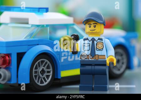 Tambow, Russische Föderation - 02. November 2024 Eine Lego-Minifigur mit Taschenlampe neben einem Polizeiauto. Stockfoto