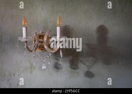 Nahaufnahme einer Wandleuchte im klassischen Stil an einer Gipswand. Strukturierte dekorative hellgrüne Putzwand mit Vintage-Wandleuchte. Hintergrund. Stockfoto