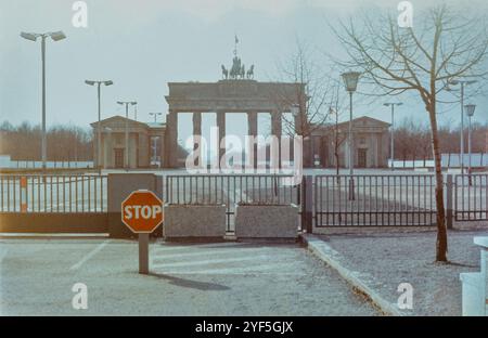 Berlin, Deutschland. Ca 1986. Das Brandenburger Tor symbolisierte das geteilte Deutschland, hier ca. 3 Jahre vor dem Fall der Berliner Mauer. Im Vordergrund sind ein Zaun und ein rotes Stoppschild, das den Zugang zum Pariser Platz verwehrt. Im Hintergrund ist das Brandenburger Tor mit der Berliner Mauer direkt dahinter zu sehen. - Das ist und Archivbild. Stockfoto