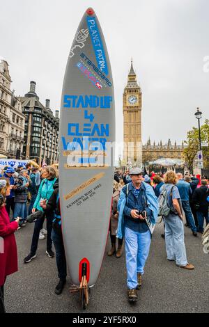 London, Großbritannien. November 2024. Ein Surfer sagt: „Steh Up for Clean Water“ - der Marsch für sauberes Wasser erreicht den Parliament Square - Extinction Rebellion tritt einer Koalition von River Action, Greenpeace & Surfers gegen Abwasser und führenden Persönlichkeiten wie Chris Packham bei einem friedlichen Protest bei, der sauberes Wasser und echte Rechenschaftspflicht fordert. Sie weisen darauf hin, dass "Großbritannien das einzige Land der Welt mit einem vollständig privatisierten Wassersystem ist, wir jedoch mit 1.000 illegalen Abwasserdeponien konfrontiert sind und dass Unternehmen 78 Milliarden Pfund an Gewinnen gemacht haben". Guy Bell/Alamy Live News Stockfoto
