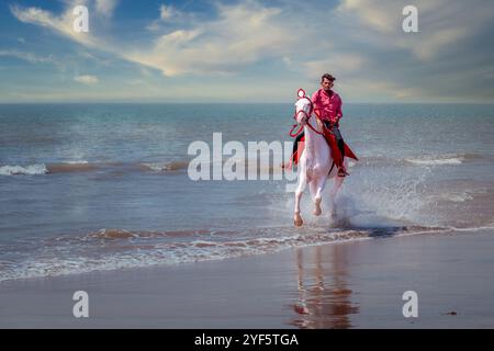 Mann reitet zu Pferd am Mandvi Beach, Gujarat, Indien Stockfoto