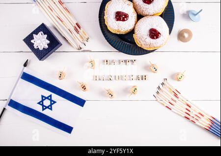 Eine festliche Kulisse für die jüdische Hanukka. Blick von oben auf einen weißen Holztisch mit traditionellen Symbolen, Leckereien für den Urlaub. Der Text des Wunsches Stockfoto