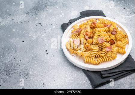 Carbonara-Pasta mit knusprigen Speckstückchen und Parmesankäse auf einem Teller. Grauer Hintergrund. Draufsicht. Stockfoto