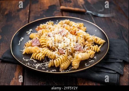 Italienische Carbonara-Pasta mit knusprigen Speckstückchen auf einem Teller. Hölzerner Hintergrund. Draufsicht. Stockfoto