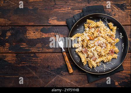 Italienische Carbonara-Pasta mit knusprigen Speckstückchen auf einem Teller. Hölzerner Hintergrund. Draufsicht. Stockfoto