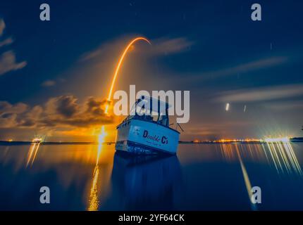 Ein Falcon 9 steigt im Juli 2024 hinter einem Boot auf dem Banana River in Florida in den Weltraum auf. Stockfoto