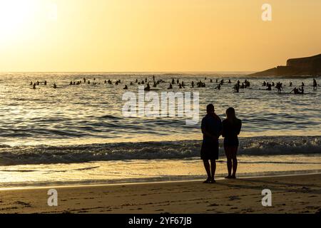 Menschen am Strand und auf SUP-Boards beobachten den Sonnenaufgang am Copacabana Beach in Rio de Janeiro in Brasilien Stockfoto