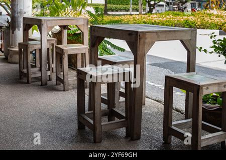 Café im Freien mit Holztischen und Hockern in einer Stadtstraße. An einem sonnigen Sommertag stehen Holztische, Hocker und Stühle in einem Café im Freien. Ein gemütliches Ou Stockfoto