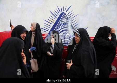 Teheran, Iran. November 2024. Iranische Frauen laufen an einem Wandgemälde entlang der Mauer der ehemaligen US-Botschaft während einer Anti-US-Kundgebung zum 45. Jahrestag der Übernahme durch die US-Botschaft vor dem ehemaligen Botschaftsgebäude vorbei. Am 4. November 1979 übernahmen iranische Studenten die US-Botschaft in Teheran und hielten über 50 amerikanische Diplomaten und Wärter 444 Tage lang als Geiseln. Diese Aktion folgte der Entscheidung der USA, dem entlassenen Schah aus dem Iran die medizinische Behandlung in Amerika zu erlauben. Vor kurzem, am 2. November, warnte der Oberste Führer Ayatollah Ali Khamenei vor einer ernsten Reaktion auf die USA und Israel Stockfoto