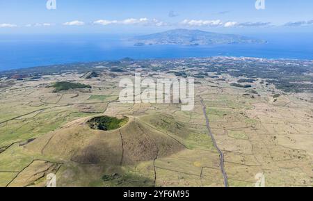 Luftaufnahme des westlichsten Teils der Insel Pico mit dem Vulkankrater Cabeco Gordo im Vordergrund und der Insel Faial in der Ferne - Azoren Stockfoto