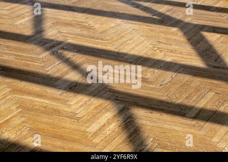 Abstrakter Hintergrund mit geraden Schatten von einem Fensterrahmen auf altem Holzparkett-Nahaufnahme. Stockfoto