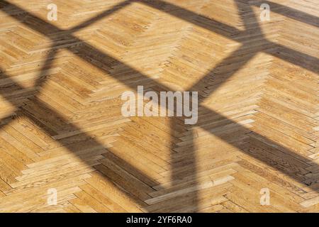 Abstrakter Hintergrund mit geraden Schatten von einem Fensterrahmen auf altem Holzparkett-Nahaufnahme. Stockfoto