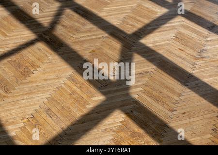 Abstrakter Hintergrund mit geraden Schatten von einem Fensterrahmen auf altem Holzparkett-Nahaufnahme. Stockfoto