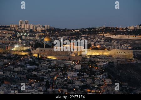Panoramablick auf die alten Mauern der Altstadt von Jerusalem mit dem goldenen Felsendom, der in der blauen Stunde bei Dämmerung beleuchtet wird. Stockfoto