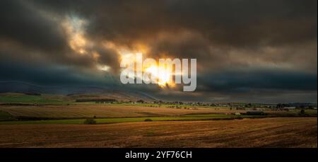 Dramatischer Himmel bei Sonnenuntergang über dem Dorf Thankerton, South Lanarkshire, Schottland Stockfoto