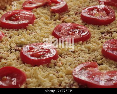 Frische Tomaten- und Käsescheiben auf einem rustikalen Backblech für Pizza. Reife Tomaten- und Käsescheiben werden für die Pizzazubereitung ordentlich auf eine Holzoberfläche gelegt. Stockfoto
