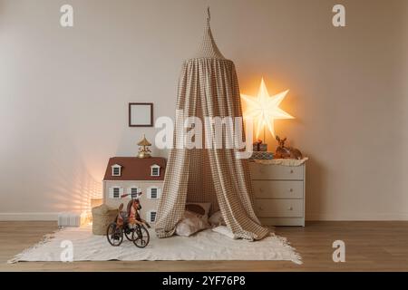 Nahaufnahme eines Pferdespielzeugs vor einem Puppenhaus, Zelt-Tipi und Kommode mit eingewickelten Geschenken im Kinderzimmer Stockfoto