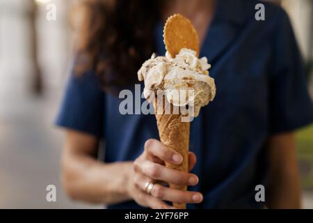 Frau, die auf der Straße steht und einen Waffelkegel mit Pistazien und Stracciatella-Eis, Schlagsahne und Keks hält, Amalfiküste, Italien Stockfoto