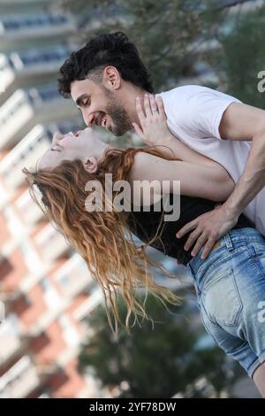 Fröhlich liebendes junges Paar, das Spaß im Stadtpark hat, umarmt und lacht Stockfoto