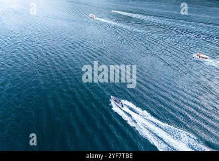 Hochgeschwindigkeitsboote, die an einem sonnigen Tag durch das ruhige blaue Wasser fahren Stockfoto