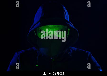 Kein Computerhacker mit weißer Maske, der Daten von einem Laptop klaut. Maskierter Hacker, der einen Laptop verwendet, um massive Angriffe auf Datenmissbrauch zu organisieren Stockfoto