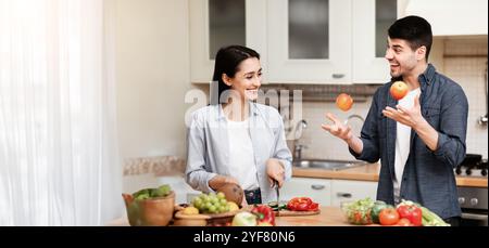 Schönes Paar, das das Abendessen mit Äpfeln jongliert Stockfoto