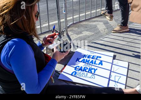 New York, USA. November 2024. Ein Zuschauer schreibt ein Schild, das die demokratische Präsidentschaftskandidatin Kamala Harris unterstützt, während sie am Rande des NYC-Marathons auf Läufer wartet. Mehr als 50.000 Läufer aus aller Welt nahmen am NYRR TCS New York City Marathon 2024 Teil, zwei Tage vor den US-Präsidentschaftswahlen. Quelle: Enrique Shore/Alamy Live News Stockfoto