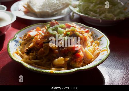 Pasta mit Meeresfrüchten eine Garnitur mit gehackten Frühlingszwiebeln, Hintergrundbeleuchtung, Beilagen, Brotbutter, Meeresfrüchten, dekorierter Teller, Norfolk, UK Stockfoto