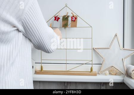 Nummer auf Bastelpapieren mit Aufgaben vor den Weihnachtsferien. Frau, die Kraftpapier für handgemachten Adventskalender herstellt, mit eigenen Händen Schritt für Schritt DIY Basteln machen Sie es selbst Stockfoto