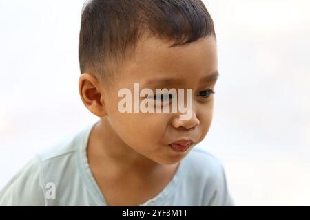 Ein kleiner Junge zeigt einen nachdenklichen Ausdruck, der in sanfter Beleuchtung festgehalten wird. Sein ruhiges Auftreten weckt Emotionen der Neugier und Unschuld, perfekt für Familien Stockfoto