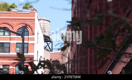 New York City Manhattan Gebäudearchitektur. Städtisches Wohnhaus außen. Immobilien in den USA. Rote Ziegelfassade. Feuerleiter, Notausstieg. Wasserturm auf dem Dach, Tank auf dem Dach. Stockfoto