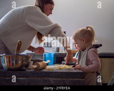 Mutter und Töchter backen Kekse zusammen in der gemütlichen Küche und füllen den Raum mit Lachen, während sie Kekse Formen und dekorieren. Dieser süße Familienmoment Stockfoto