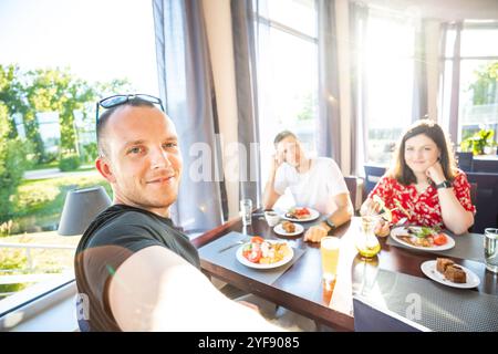 Sonnendurchflutete, zwanglose Speiseszene mit Freunden, die gemeinsam ein Essen in einem modernen Restaurant genießen Stockfoto