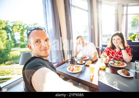 Sonnendurchflutete, zwanglose Speiseszene mit Freunden, die gemeinsam ein Essen in einem modernen Restaurant genießen Stockfoto