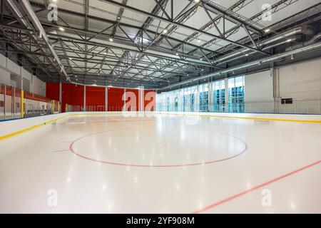 Elegante Eislaufbahn in einer modernen Anlage mit weitläufigen Glaswänden und Metallrahmen Stockfoto