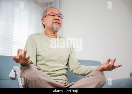 Ein alter asiatischer Mann übt Yoga und Meditation in Lotusposition und mit geschlossenen Augen Stockfoto