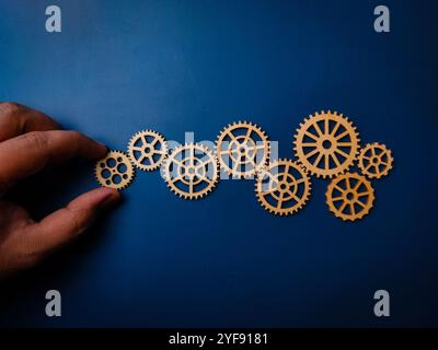 Hand hält hölzerne Ausrüstung auf blauem Hintergrund. Automatisierung von Geschäftsprozessen und Workflows. Stockfoto