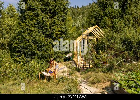 Frau baut ein Holzgewächshaus im Hinterhof Stockfoto