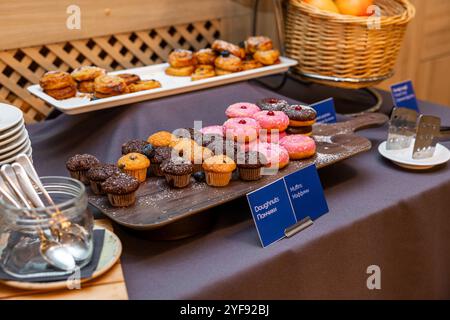 Köstliches Frühstück mit Donuts, Muffins und frisch gebackenem Gebäck an einem Buffet-Tisch im Hotel Stockfoto